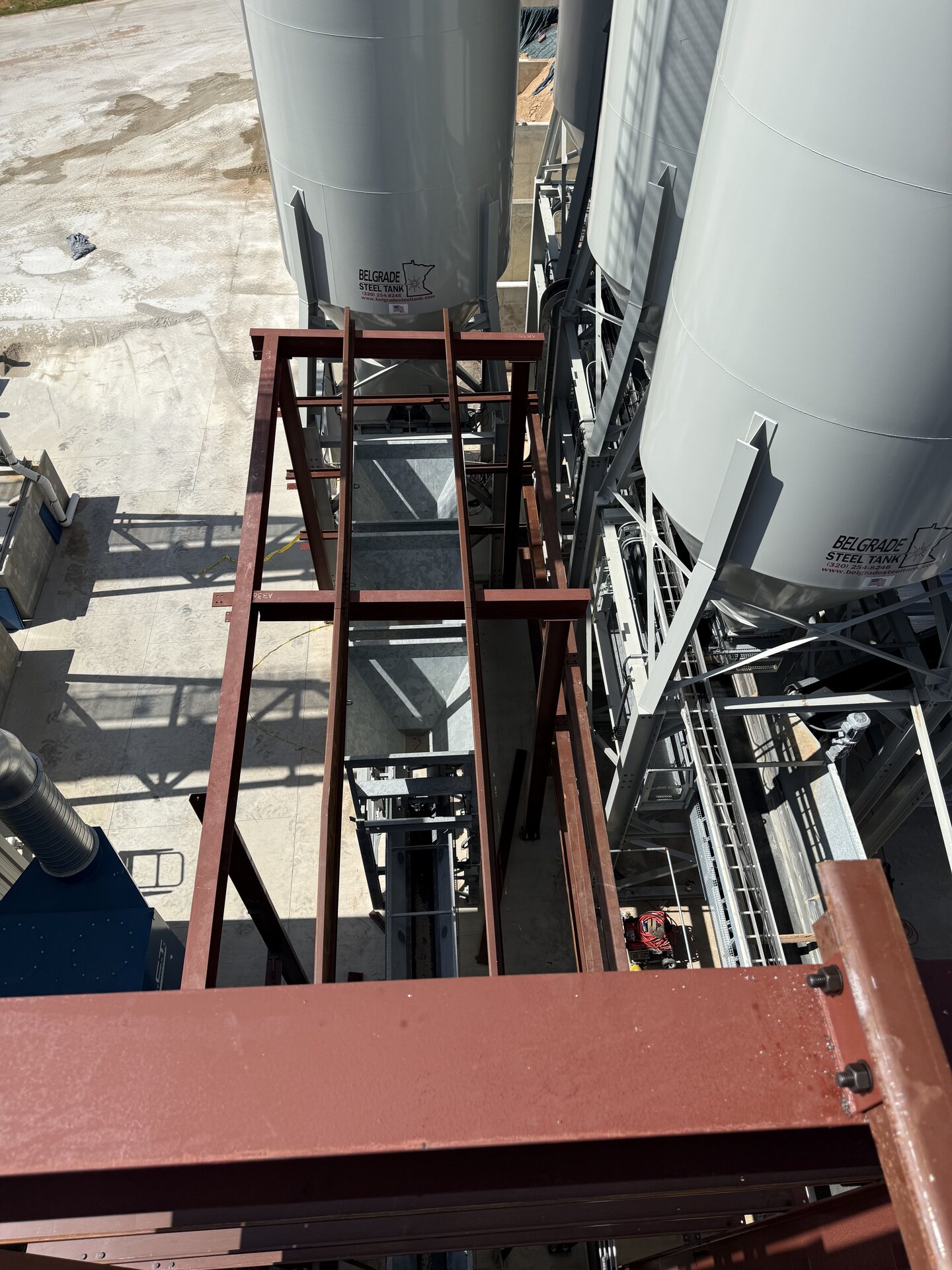 Elevated view of primed structural steel framing alongside the Oldcastle plant silos
